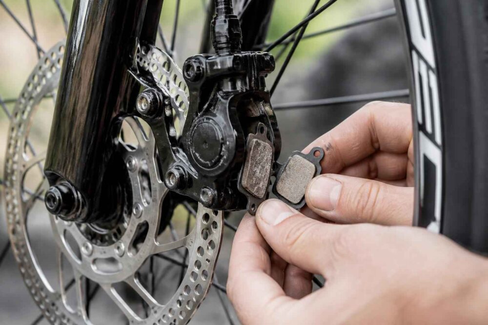 Dłonie montujące klocki hamulcowe przy tarczy hamulcowej roweru disc brake